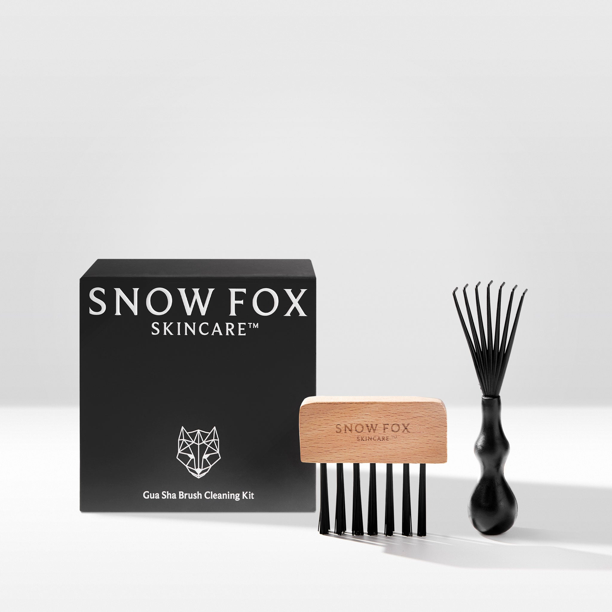 A Gua Sha Brush Cleaning Kit by Snow Fox Skincare, consisting of a rake brush and a bristle brush, displayed alongside its packaging.