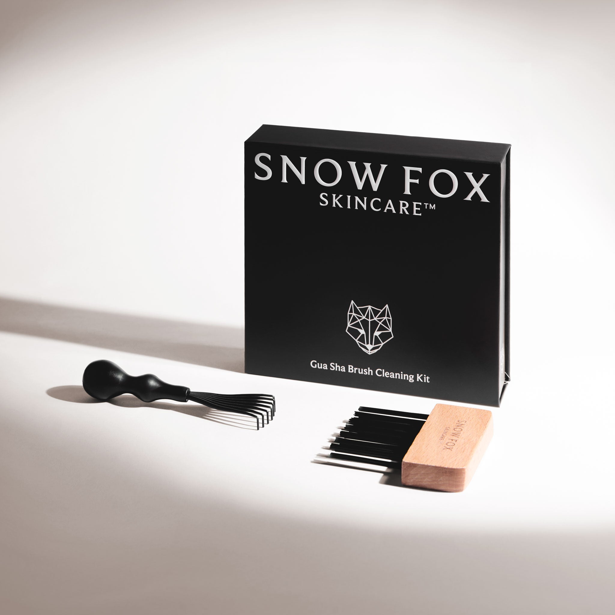 the Snow Fox Skincare Gua Sha Brush Cleaning Kit with the rake brush and bristle comb for brush pad next to each other on a light beige background