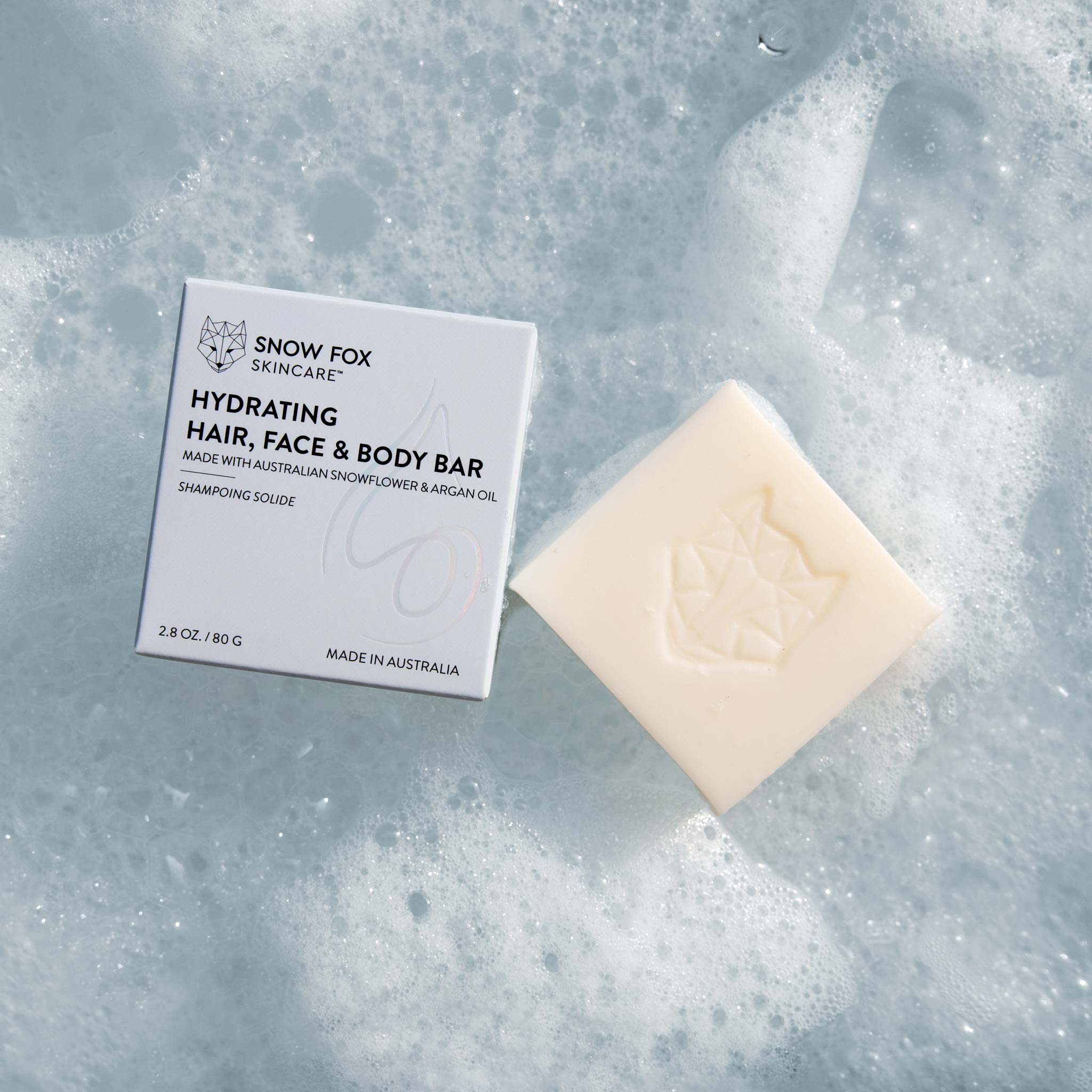 Snow Fox Skincare hydrating hair, face & body cleansing bar on a textured bubbly surface