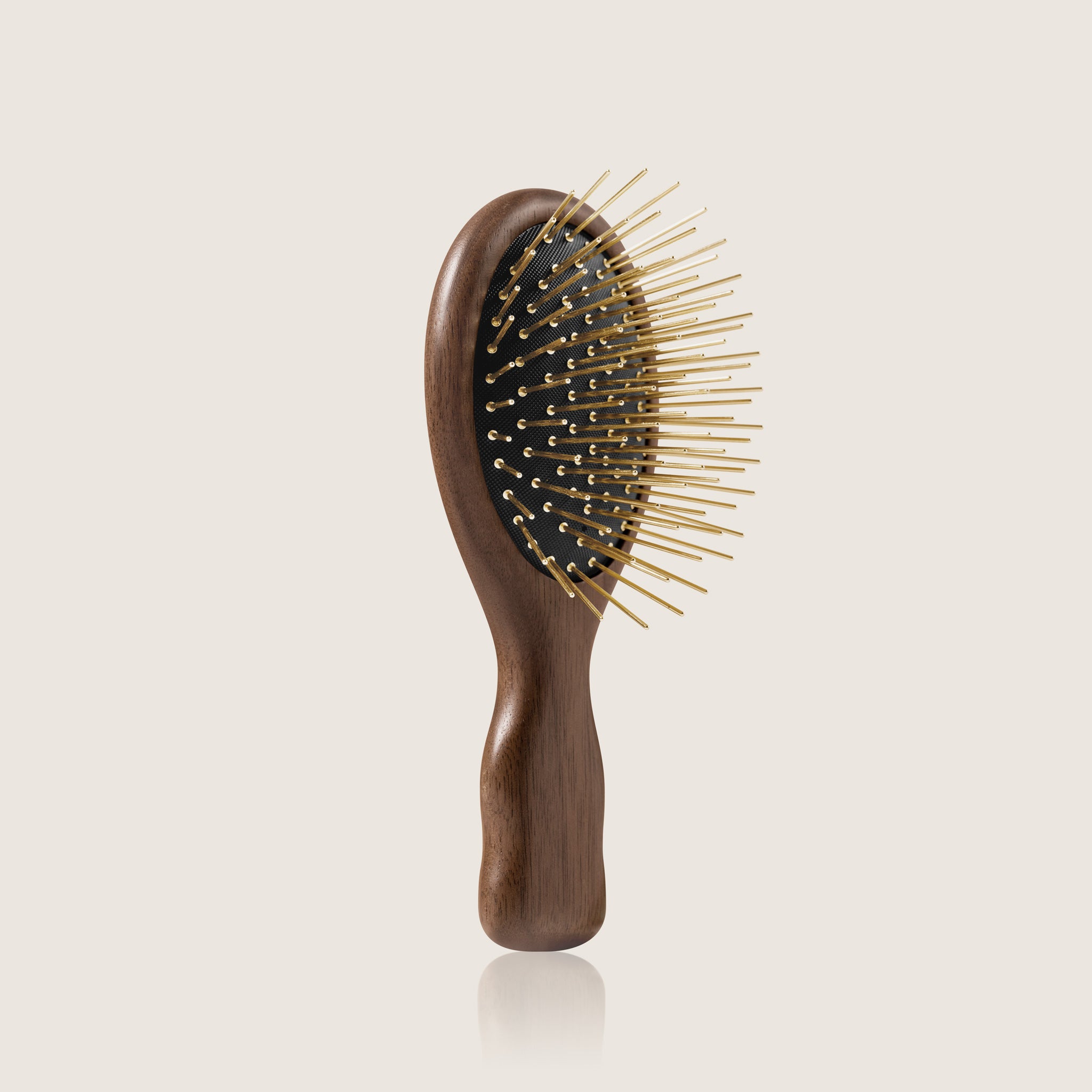 Infrared Walnut wood Gua Sha hairbrush with 24K gold plated acupressure needles on a beige background