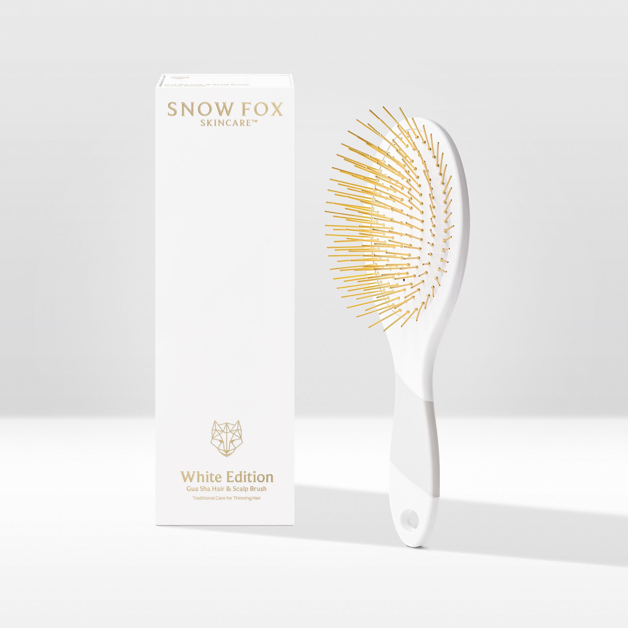 White Edition Thermoplastic Gua Sha Brush by Snow Fox Skincare on a white and grey background