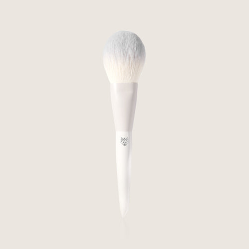 Fluffy vegan Fox Tail makeup brush by Snow Fox Skincare on a light beige background