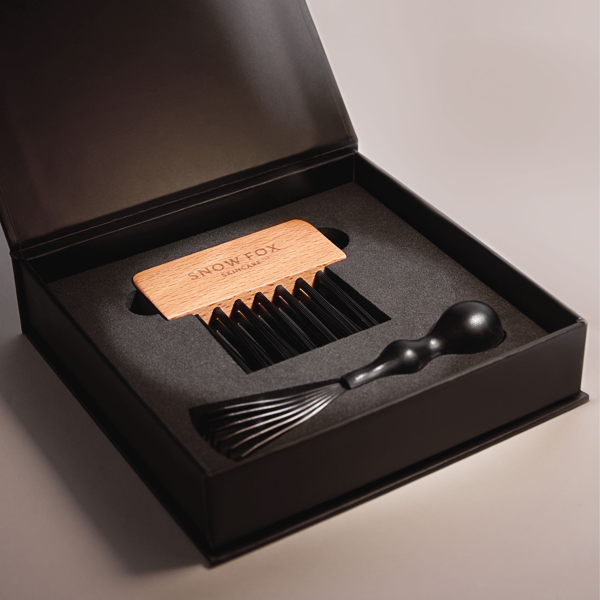 the Snow Fox Skincare Gua Sha Brush Cleaning Kit with the rake brush and bristle comb for brush pad inside the box on a light beige background 