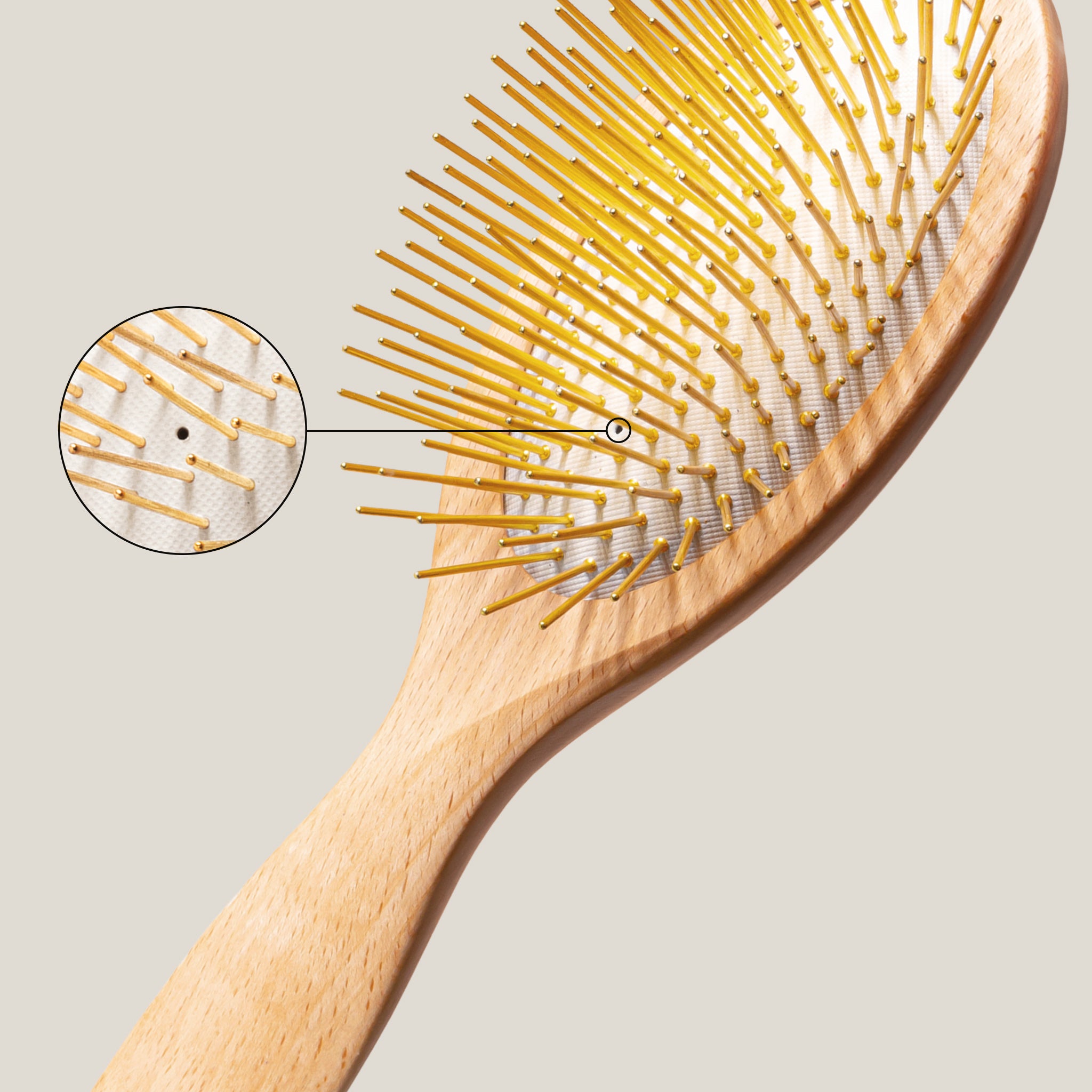 Wooden Gua Sha Acupressure hairbrush with close-up of gold needle design on a light gray background